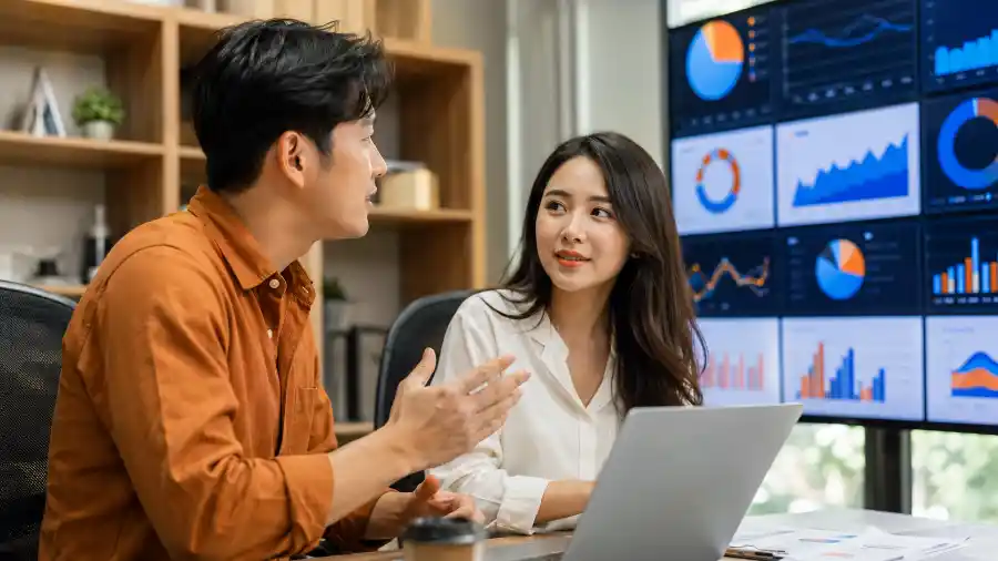 Nhịp AI tuần 26: hai chuyên viên trẻ Việt Nam trao đổi trước màn hình dữ liệu AI tại văn phòng